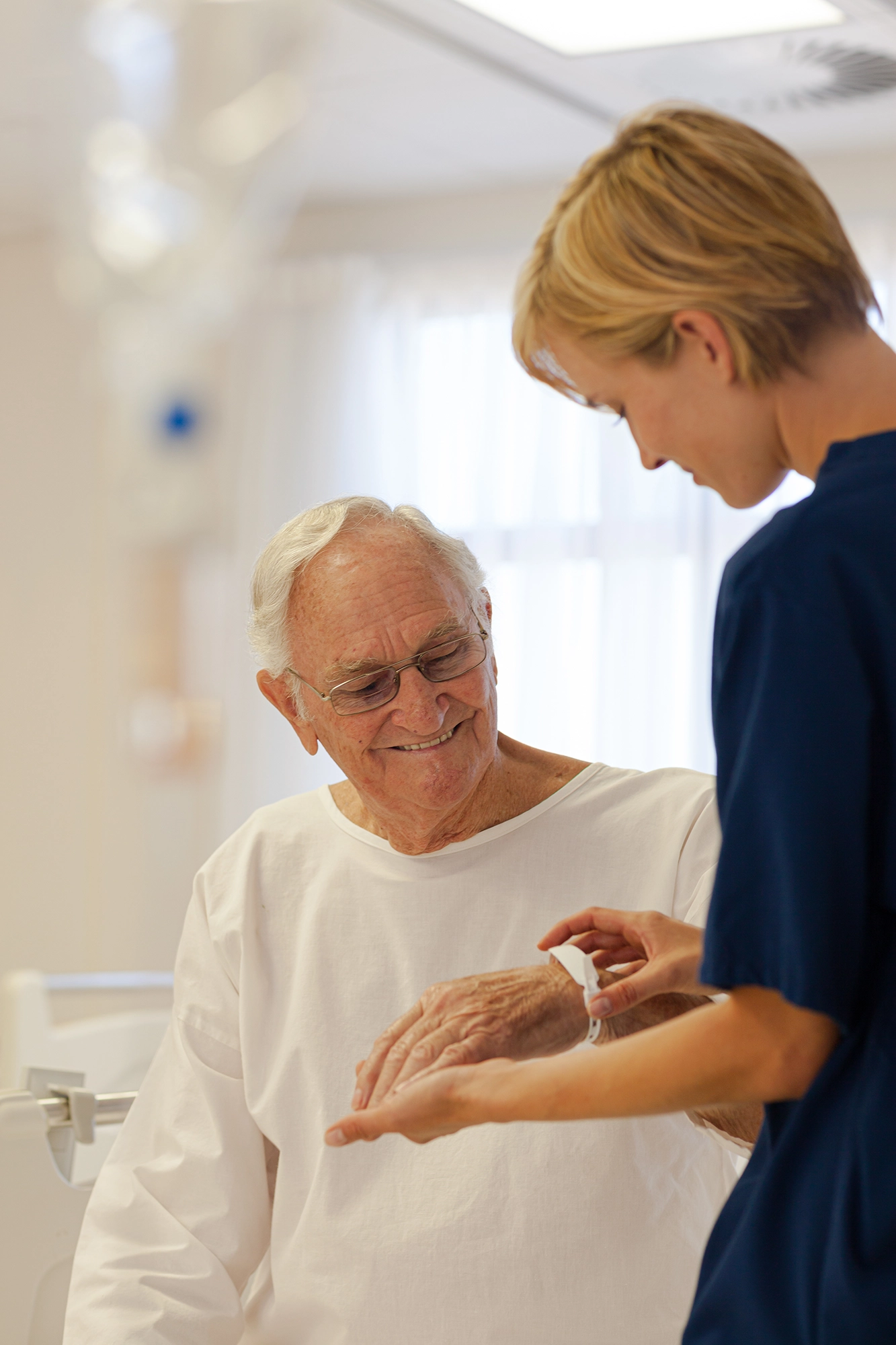 Infirmi&egrave;re posant un bracelet d&rsquo;identification &agrave; un patient &acirc;g&eacute; &agrave; l&rsquo;h&ocirc;pital